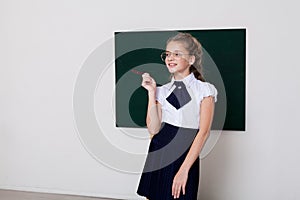 Schoolgirl girl stands at school board in classroom