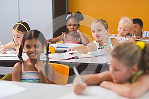 Schoolgirl giving chit to her friends in classroom photo