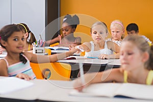 Schoolgirl giving chit to her friends in classroom photo