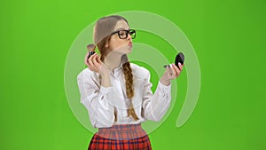 Schoolgirl in glasses powdered her nose with a brush. Green screen