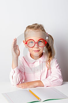 A schoolgirl with glasses at a table