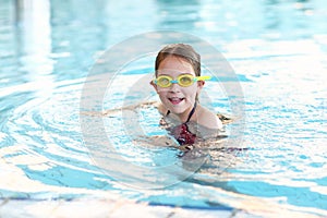 Schoolgirl with goggles in swimming pool