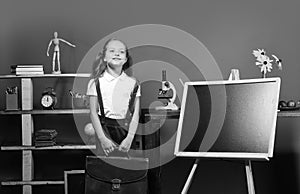 Schoolgirl with happy face in her classroom. Education and back to school concept. Kid and school supplies