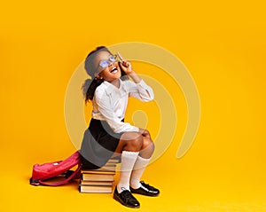 Schoolgirl Having Idea Pointing Finger Up Sitting On Books, Studio