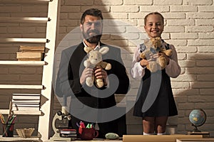 Schoolgirl and her dad with smiling faces hold soft toys