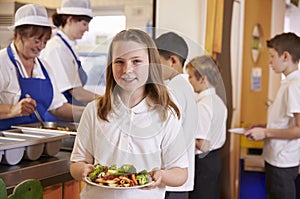 Schoolgirl holding a plate of food in a school cafeteria