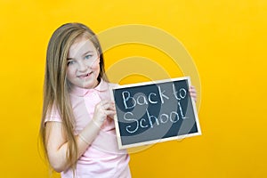 Schoolgirl holding a tablet in her hands with the inscription Back to school on a yellow background