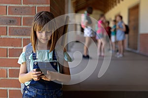 Schoolgirl leaning against a wall in the schoolyard at elementary school