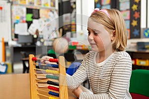 Schoolgirl learning mathematics with abacus in the classroom