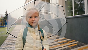 Schoolgirl little girl going holding umbrella rain weather damp cloudy after lessons elementary school walk stroll child