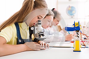Schoolgirl looking at microscope at stem robotic class