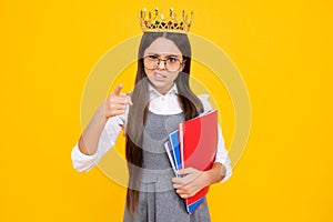 Schoolgirl nerd princess in school uniform and crown celebrating victory on yellow background. School child hold book