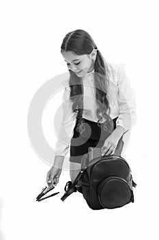 Schoolgirl packing backpack isolated on white. Little child put pen and book into bag. Pack backpack for lessons