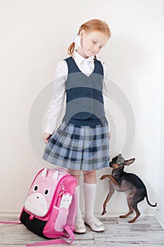 Schoolgirl with a pink briefcase and dog indoors