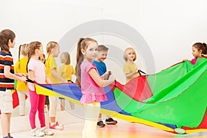 Schoolgirl playing parachute with friends in gym