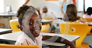 Schoolgirl raising hand in classroom