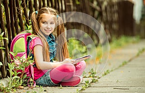 Schoolgirl reading a book on the street