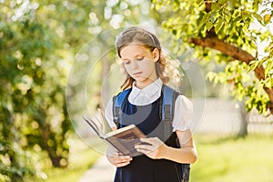 Schoolgirl reads book outdoors