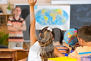 Schoolgirl rising her hand at geography lesson