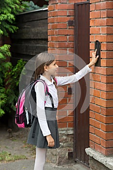 Schoolgirl with rucksack ringing in doorbell