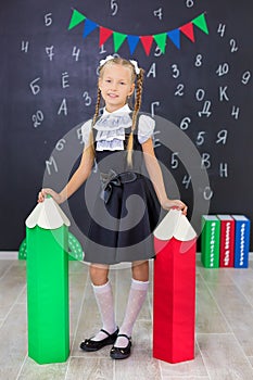 The schoolgirl in school uniform with books and textbooks is on a light gray background. Back to school. The new school year. photo