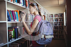 Schoolgirl selecting book in library