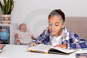 The schoolgirl siting at the table at home and doing his homework