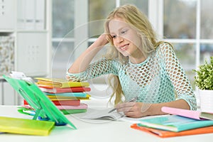 Schoolgirl sitting at desk and studying at home