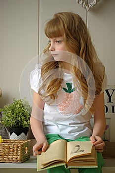 Schoolgirl sitting at home with a book in hand