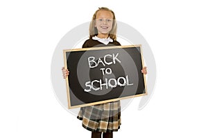 Schoolgirl smiling happy holding and showing small blackboard with text back to school