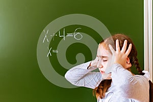 Schoolgirl solves a math problem on blackboard during the lesson