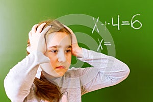 Schoolgirl solves a math problem on the blackboard during the lesson