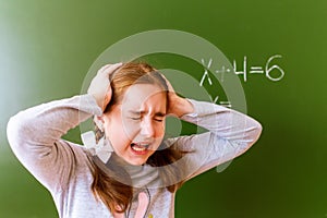 Schoolgirl solves a math problem on the blackboard during the lesson