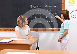 Schoolgirl solving math equations at chalkboard