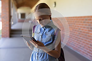 Schoolgirl standing in the schoolyard at elementary school using a tablet computer