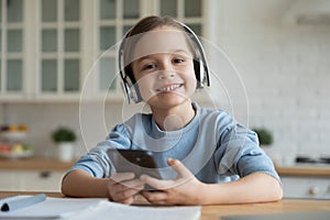 Schoolgirl study at home using wireless headphones and smartphone application