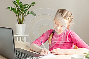 Schoolgirl studying at home using laptop. Home school, online education, home education, quarantine concept