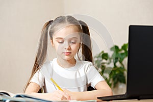 Schoolgirl studying homework during her online lesson at home, online education and online school concept, home schooler. Distance