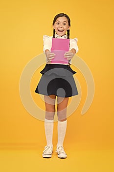 Schoolgirl studying textbook. Kid girl school uniform happy face read book studying. Excited about knowledge. Enjoy