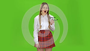 Schoolgirl takes off her glasses and yawns. Green screen