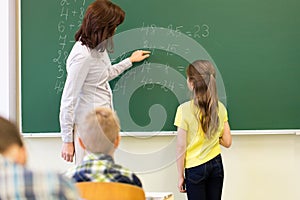 Schoolgirl and teacher with task on chalk board