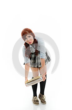 Schoolgirl trying to lift a heavy stack of books