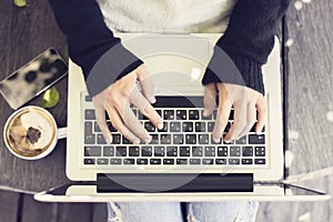 Schoolgirl typing on a laptop, with cell phone and coffee