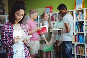 Schoolgirl using digital tablet in library