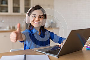 Schoolgirl Using Laptop Gesturing Thumbs Up Approving Online Lecture Indoors