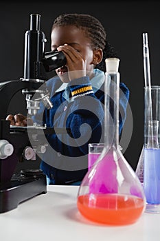 Schoolgirl using microscope against black background