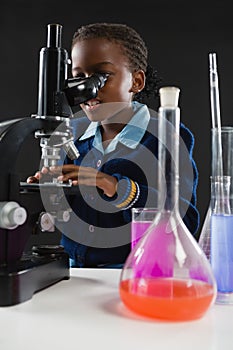 Schoolgirl using microscope against black background