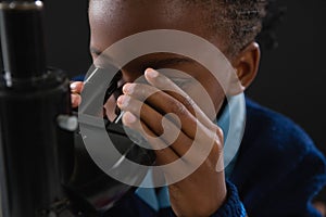 Schoolgirl using microscope against black background