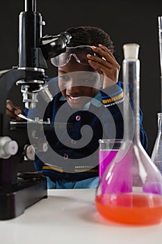 Schoolgirl using microscope against black background