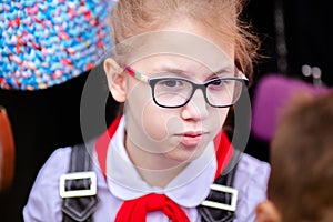 A schoolgirl in a white blouse with a red tie, with a bow in the class. Back to school concept